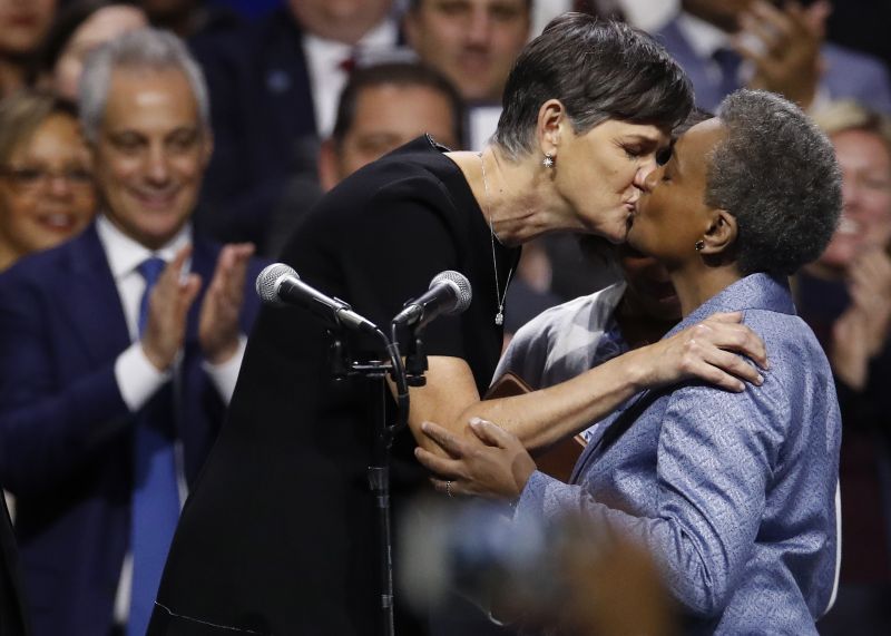 Chicago Mayor Lori Lightfoot, right, kisses her spouse Amy Eshleman as outgoing Mayor Rahm Emanuel looks on during her inauguration ceremony Monday, May 20, 2019, in Chicago. (AP Photo/Jim Young) 