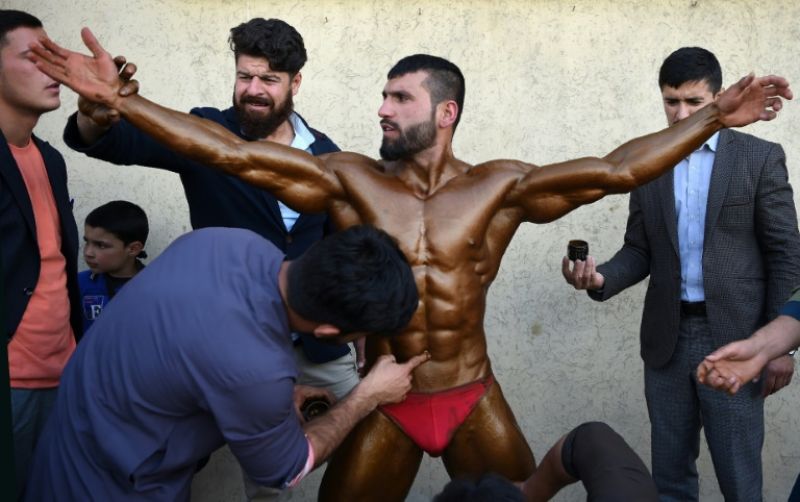 Bodybuilder Hares Mohammadi, 25, being covered in fake tan during a contest in Kabul. (Photo: AFP)