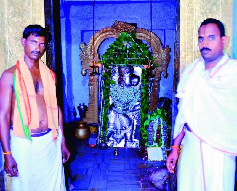 Priests stand before the idol of Lord Anjaneya. 