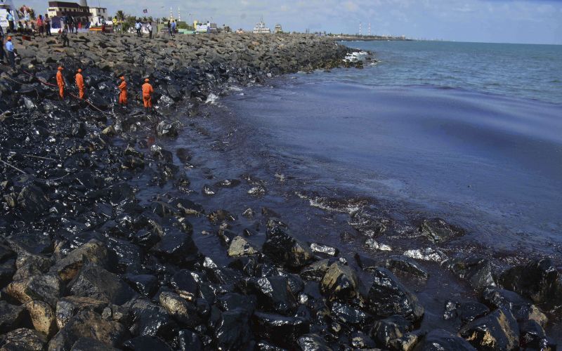 Coast Guard personnel work to clear the slick after an oil spill polluted the Ennore beach on the Bay of Bengal coast near Chennai. (Photo: AP)