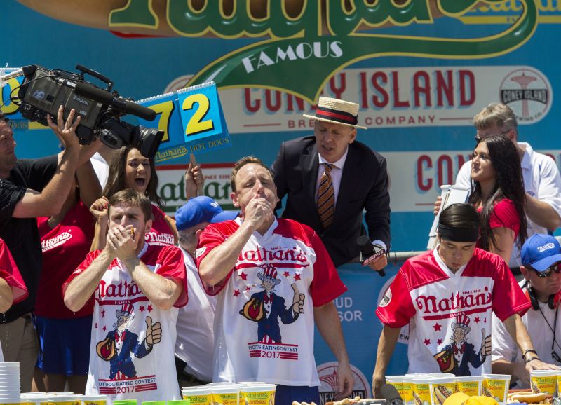 Carmen Ciccotti, left, Joey Chestnut, center, and Matt Stonie compete in the Nathan's Famous Hotdog eating contest Tuesday, July 4, 2017, in Brooklyn, New York. Chestnut ate 72 hotdogs in 10 minutes to claim his 10th win.(AP Photo/Michael Noble Jr.)