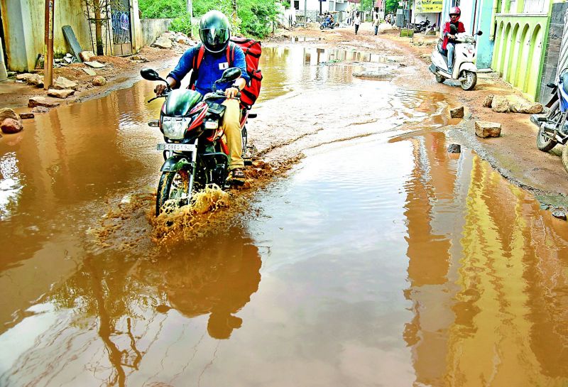 A biker rides through a pool of stagnant water on the road in Hasmatpet, Old Bowenpally. (Photo: S. Surender Reddy)
