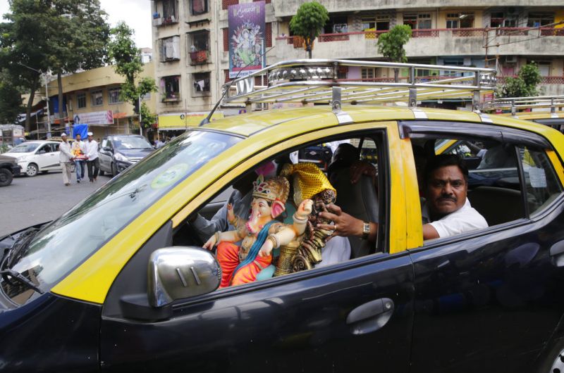 Devotees carry home an idol of elephant-headed Hindu god Ganesha in a taxi for worship during Ganesh Chaturthi festival celebrations in Mumbai. (Photo: AP)