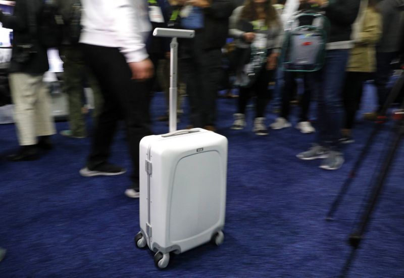 A man demonstrates the Ovis Suitcase at the ForwardX booth during CES Unveiled at CES International, Sunday, Jan. 6, 2019, in Las Vegas. The suitcase will automatically follow the user at their side as they walk. (AP Photo/John Locher)