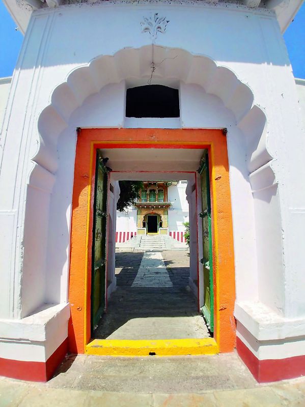 A view of the main temple seen through a door that has Mughal architecture influence. 