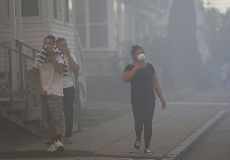 People cover their faces to protect themselves from heavy smoke from a fire on Bowdoin Street in Lawrence. (Photo: AP)
