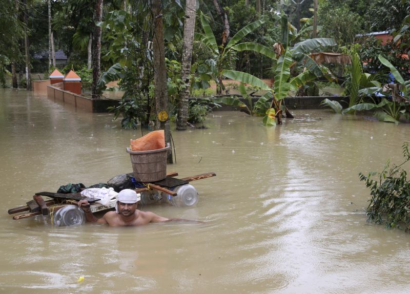 A stranded man wades through flood waters with a makeshift raft in Chengannur. (Photo: PTI)