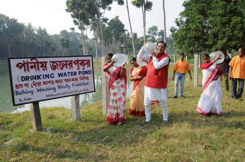 Women along with Dr Bindeshwar Pathak, founder of Sulabh International, carrying drinking water cans labelled Sulabh jal' from a water purification plant in  Madhusudan Kati 