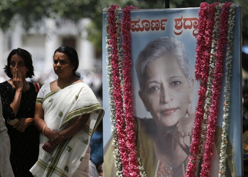 Mourners stand next to a portrait of Indian journalist Gauri Lankesh during the public viewing of her body in Bangalore. (Photo: AP)