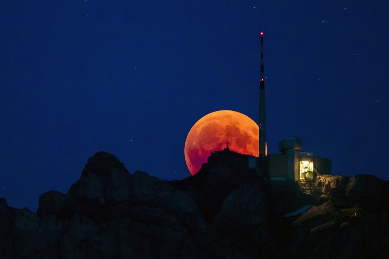 The moon turns red during a total lunar eclipse, behind the Saentis in Luzern, Switzerland, on Friday. (Photo: AP)