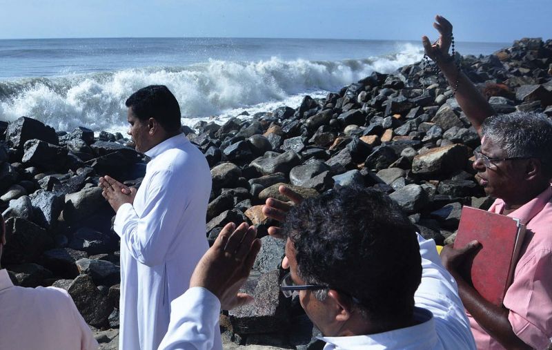 Catholic priests pray as sea continues to remain rough on Saturday.