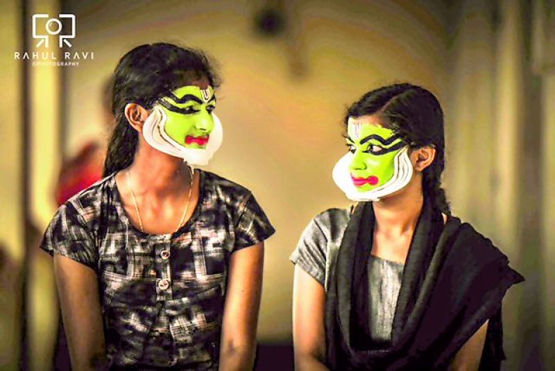 Young Kathakali artistes exchange glances during their makeup session.