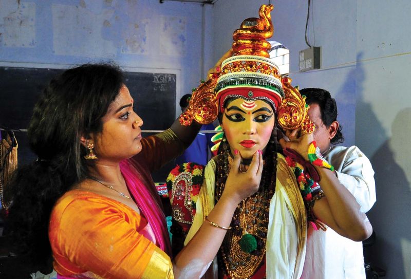 Drishya Gopinathan, the teacher of Devika V.P., helps her to don the crown to  perform Parayan Thullal in the 57th State School Kalolsavam in Kannur on Tuesday. 