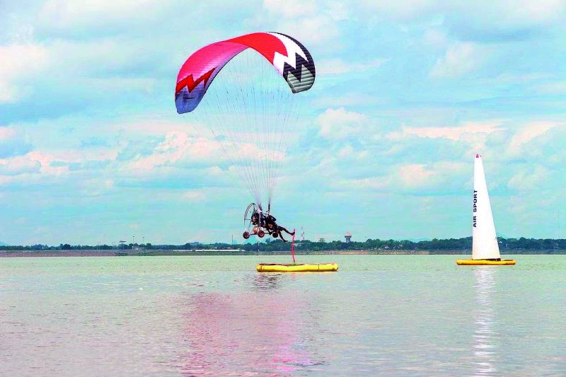 P. R. Singh refuelling his Paramotor on the eve of the World Paramotor Championship (WPC) in 2018 in Thailand and (right) Singh competing during a Slalom event on water during WPC.
