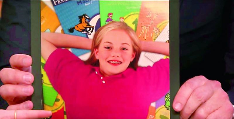 On the cover photo, a brace-faced Emma can be seen smiling and is surrounded by a spread of textbook covers: math, spelling and vocabulary, French, and others