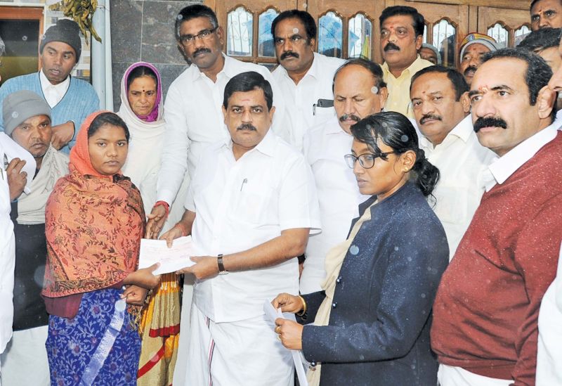  K.Radhakrishnan,  minister for animal husbandry, hands over the compensation to the member of  a flood affected family at Kuruthukuli village near Ooty on Sunday.  (Photo: DC)