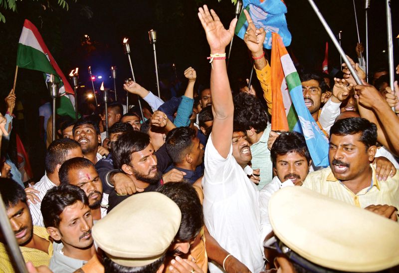 Police stop Youth Congress members who took out a torchlight rally in support of Energy Minister D.K. Shivakumar near his residence in Bengaluru on Friday. 