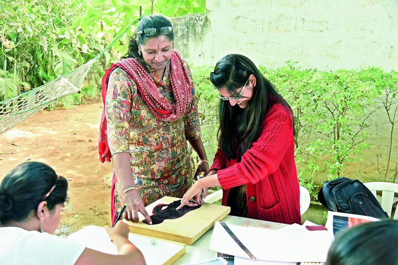 Gowri, a print making artist, demonstrates the art to a student 