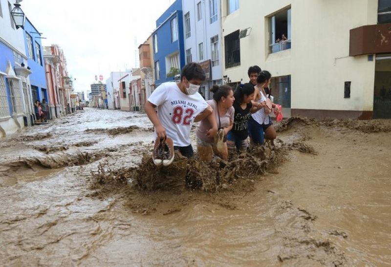 Residents wade through the water as a flash flood hits the city of Trujillo on March 18, 2017, bringing mud and debris. (Photo: AFP)