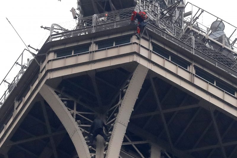 A rescue worker, top in red, climbs the Eiffel Tower while a climber is seen below him between two iron columns Monday, May 20, 2019 in Paris. The Eiffel Tower has been closed to visitors after a person has tried to scale it. (AP Photo/Michel Euler) 