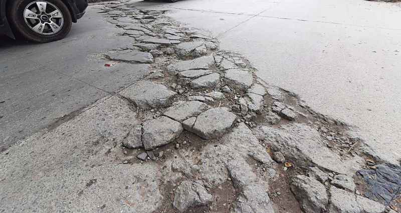 Potholes and cracks on a whitetopped road in Vasanth Nagar