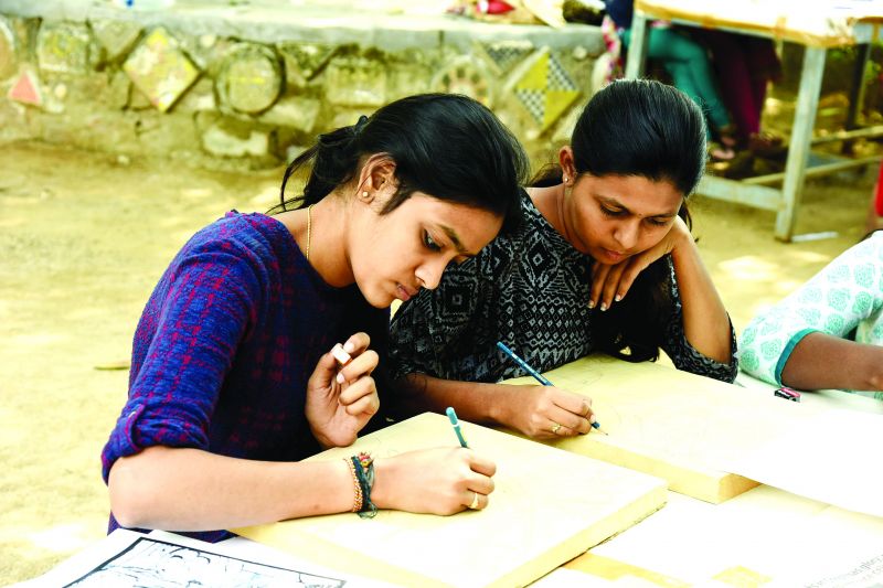 Gowri, a print making artist, demonstrates the art to a student 