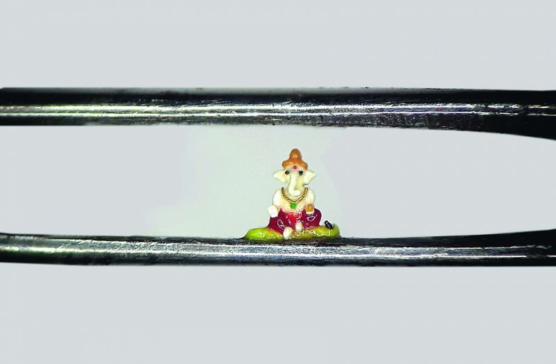 The 1.2mm miniature Ganesh idol made of wax can easily fit inside the eye of a needle. 	(Photo:DC)