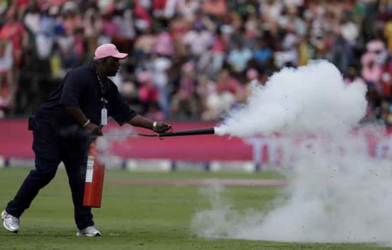 Groundsman sprays bees with a fire extinguishers after they swarmed onto the pitch. (Photo: AP)