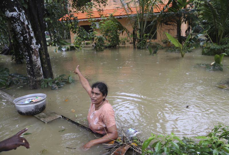 A stranded woman gestures towards her house as she asks for more essential supplies from a volunteer in a flooded area in Chengannur in Kerala. (Photo: AP)