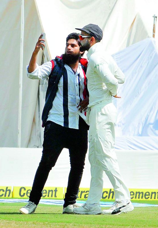 Mohammed Khan takes a selfie with Virat Kohli after running on to the ground on Friday.	 P. Surendra
