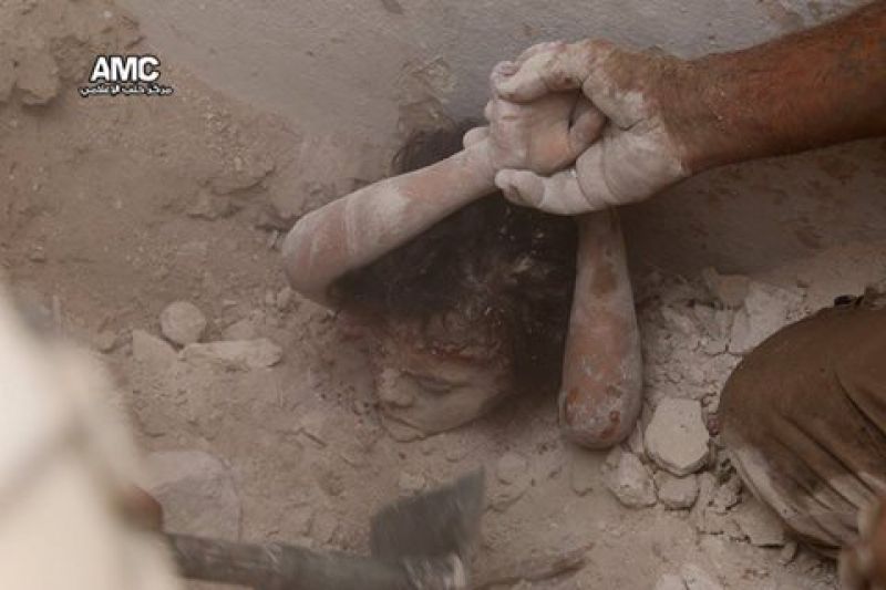 A rescue worker tries to pull out the dead body of a child buried by air strikes. (Photo: AMC/ Facebook)