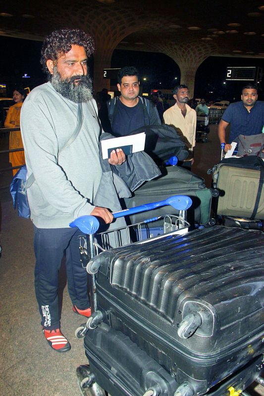 A priest accompanies the Sharma family at the  airport; (right) Anushka Sharma's brother Karnesh 