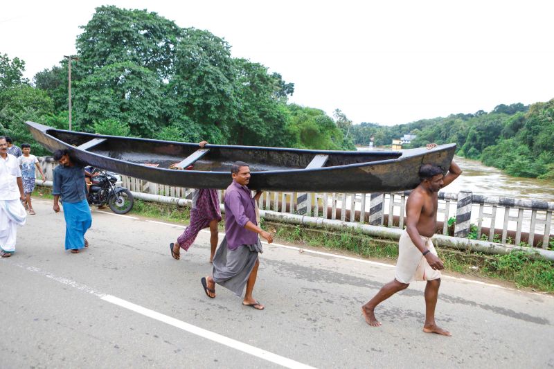 People carry a country boat to other side of Meenachil river through Mutholi bridge for rescue operations near Pala in Kottayam on Friday (Photo: RAJEEV PRASAD)