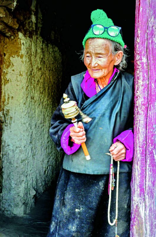 A woman silently mumbles while rotating her prayer wheels in the monastery of Lamayuru in Ladakh.