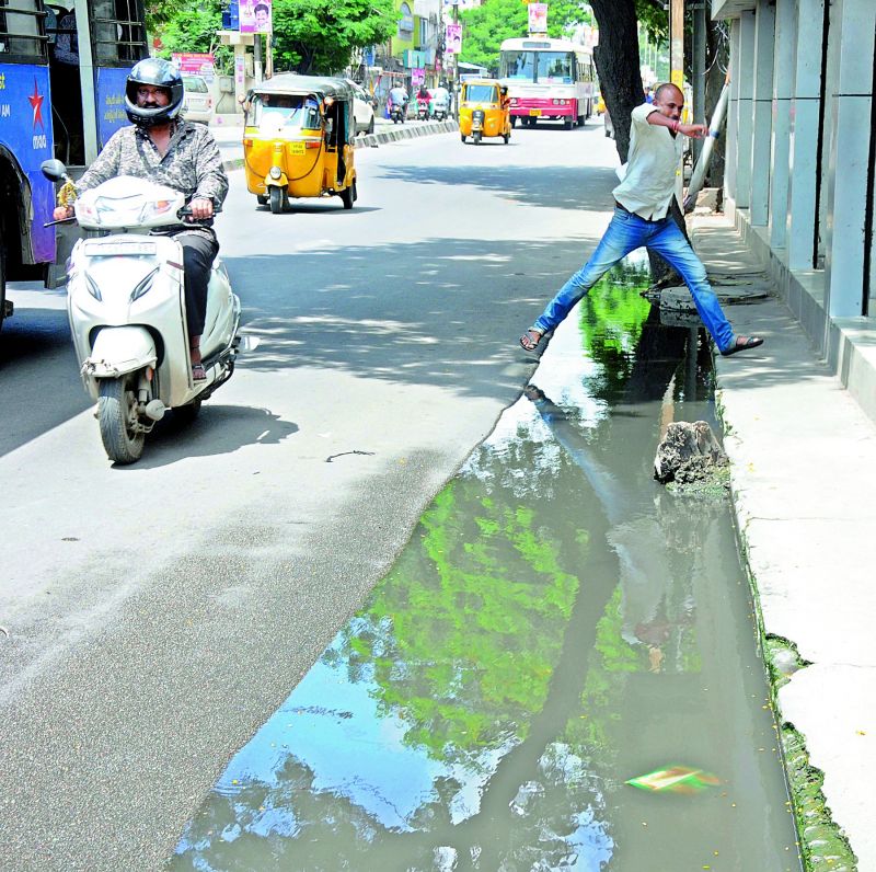 People pass through the stagnant drainage water at 6 Number signal at Amberpet (Photo: Deepak Deshpande)