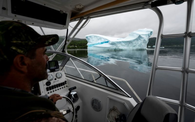 Tour guide and former fisherman Barry Strickland steers his boat near an iceberg at King's Point -- iceberg tourism has been a success for the area on Canada's eastern shores. (Photo: AFP)