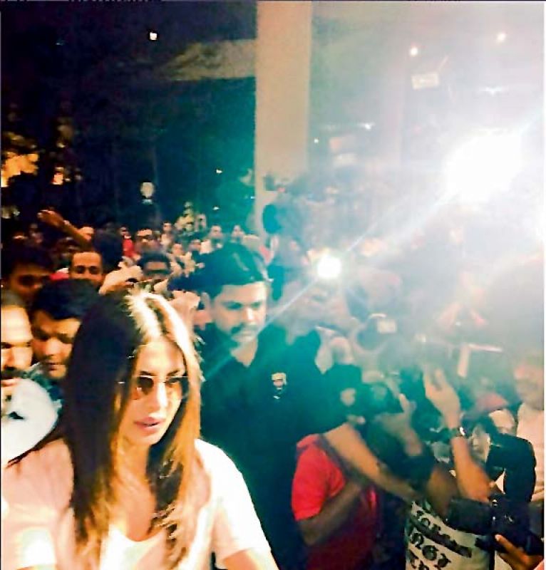 ) A picture showing PeeCee being mobbed at the Mumbai airport, after she returned to India from the US