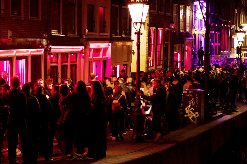 Tourists bathing in a red glow emanating from the windows and peep shows' neon lights, packed shoulder to shoulder as they shuffle through the alleys in Amsterdam's red light district. (Photo: AP)