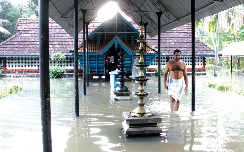 Sandheep Namboothiri, the priest, comes out of the flooded Thykattu Thrikkovil Mahavishnu Temple at Kummanam on the bank of River Meenachil in Kottayam on Monday.  (Photo: RAJEEV PRASAD)