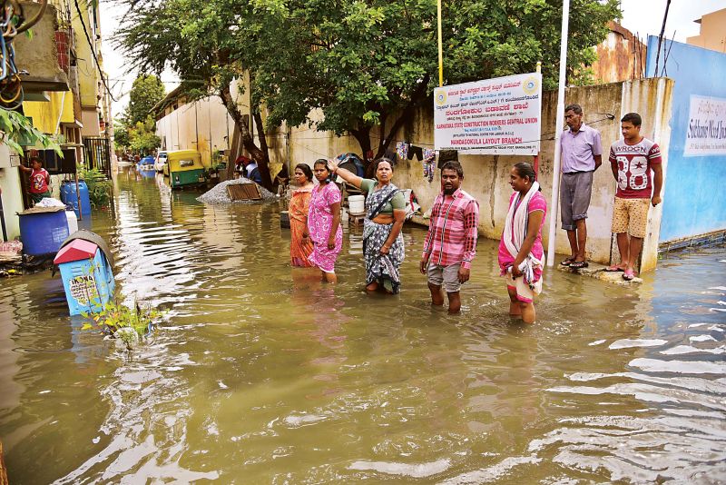 People wade through water-logged streets in Nandagokula Layout in Bengaluru on Monday. (Photo: DC)
