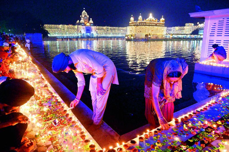 Sikh devotees lighting  diyas on the  occasion of Diwali at the  beautifully lit Golden Temple.