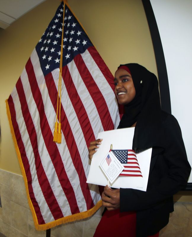 Safu Abdulhakim, who was born in Ethiopia, stands next to an American flag after she was granted her citizenship in the United States at a naturalization ceremony, Thursday, May 16, 2019, in Centennial, Colo. (AP Photo/David Zalubowski)