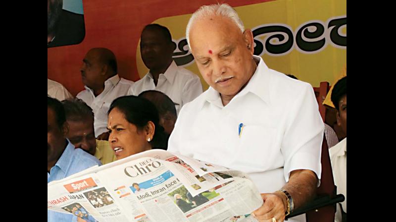 State BJP president B.S. Yeddyurappa updates himself on the days news with Deccan Chronicle, as he takes part in a dharna. (Photo: DC)