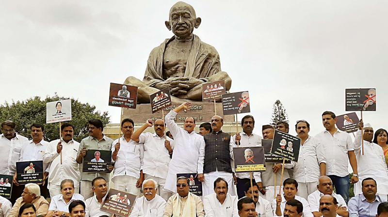 Congress leaders protest at Gandhi statue at Vidhana Soudha in Bengaluru over inadequate flood relief.