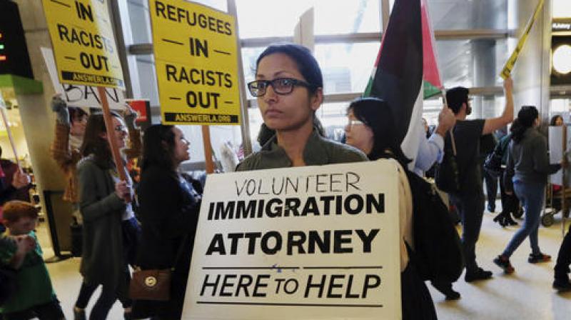 A woman offers legal services at the customs arrival area as demonstrators opposed to President Donald Trumps executive orders barring entry to the US by Muslims from certain countries march behind at the Tom Bradley International Terminal at Los Angeles International Airport. (Photo: AP)
