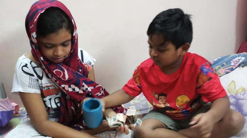 Haroon and Diya with the money from his piggybank.