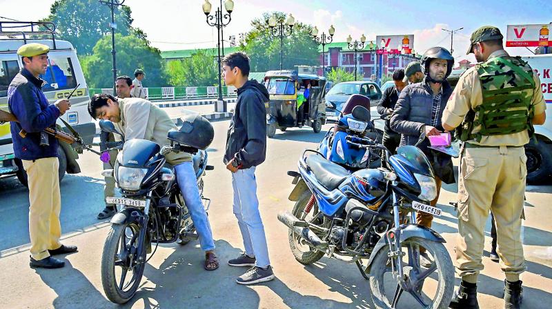 Security personnel check documents of motorcyclists  during a shut down in Srinagar on Sunday.  (PTI)
