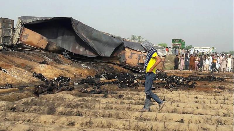 Local residents look at burnt bodies after an oil tanker caught fire following an accident on a highway near Ahmedpur East, some 670 km from Islamabad. (Photo: AFP)