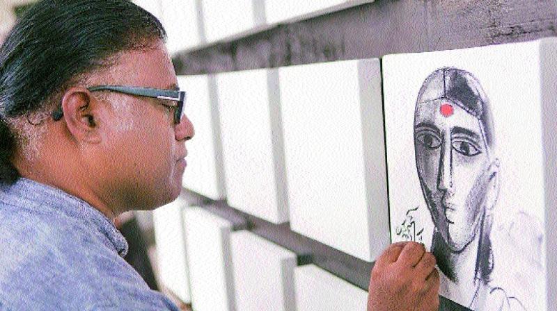 Artist Laxman Aeley gives finishing touches to his work during the artcamp in the city