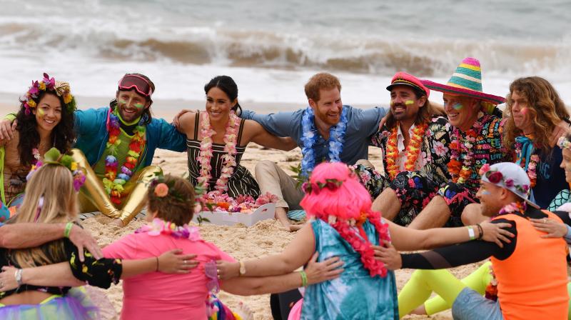 Britains Prince Harry and his wife Meghan, Duchess of Sussex join a circle during a \Fluro Friday\ session run by OneWave, a local surfing community group who raise awareness for mental health and wellbeing, at Sydneys iconic Bondi Beach on October 19, 2018. (Photo: AFP)